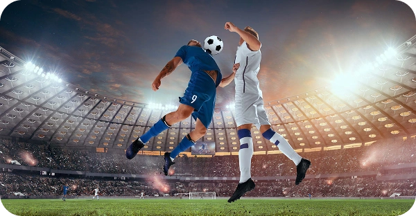 Deux joueurs de football, l'un en bleu et l'un en blanc, sautent haut pour disputer un ballon de la tête pendant un match de football